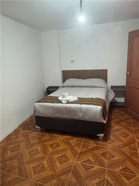 Habitación con cama matrimonial y piso de madera