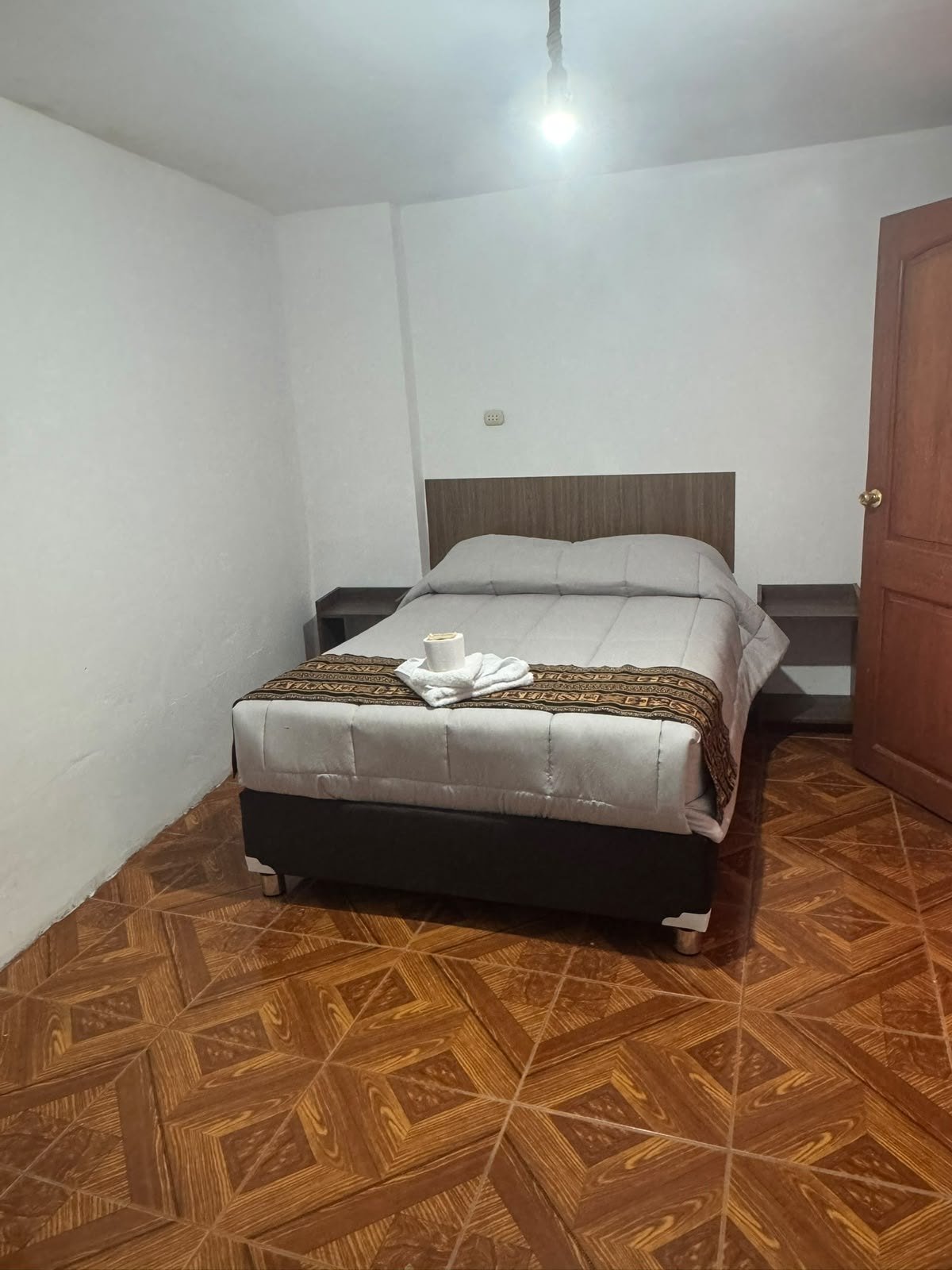 Habitación con cama matrimonial y piso de madera