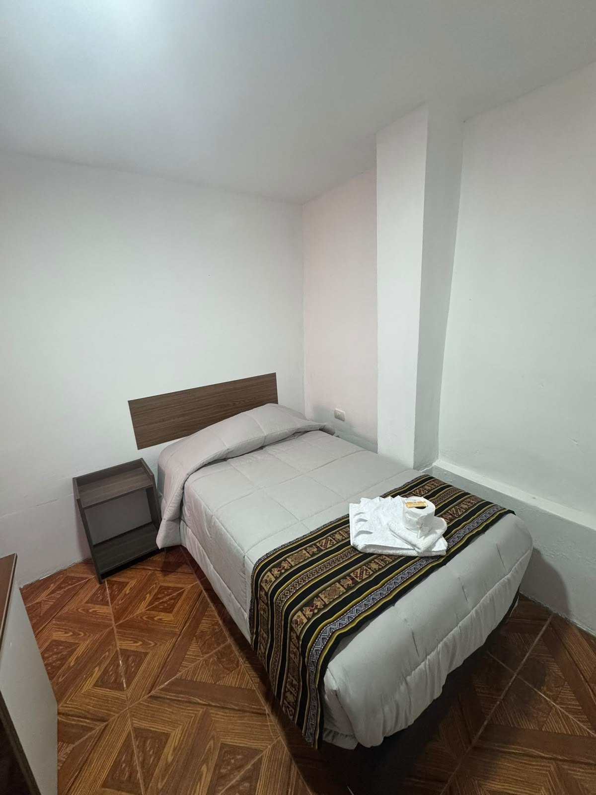 Habitación simple con ropa de cama y textiles andinos
